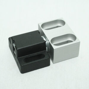 Two LEGO Technic bricks side by side: a black brick with a recessed slot and a light gray brick with two oval pin holes.