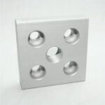 Square aluminum mounting plate with five holes: one center threaded bore and four surrounding holes for mounting.