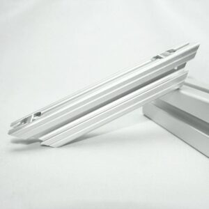 Close-up of a white aluminum extrusion rail with grooves, resting on a white surface on a neutral background.