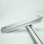 Two parallel aluminum extrusion rails connected at a joint, resting on a supporting beam against a light background.