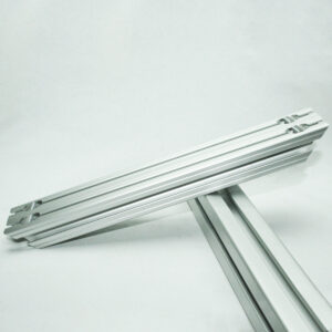 Two parallel aluminum extrusion rails connected at a joint, resting on a supporting beam against a light background.
