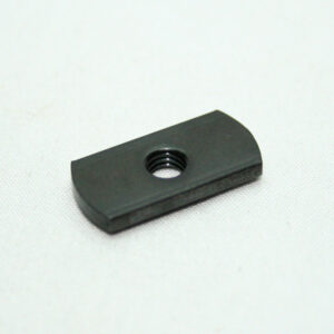 Black rectangular plate with a central threaded hole, likely a mounting spacer or insert piece on a white fabric surface.