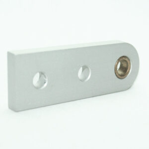 Silver machined metal block with two round holes and a threaded bore at the right end on a white surface