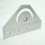 Silver triangular metal bracket with a curved slot and a central bronze bushing, resting on a flat base with five evenly spaced holes along the bottom edge.