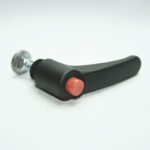 Camera shutter release button with orange top and black lever on a metal screw base (camera accessory).