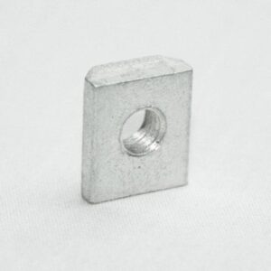 Square metal nut with a threaded hole, standing on a light surface.