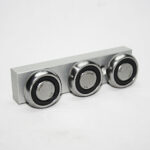 Three coin-sized silver metal components mounted along a light gray rectangular bar with black seals between them as a simple display.