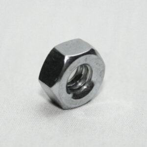 Silver metal hex nut resting on a light surface with visible internal threads inside a circular hole.
