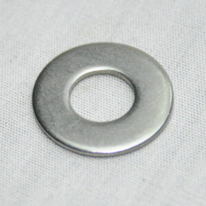 Shiny metal washer lying on light fabric background, centered and circular with a central hole.