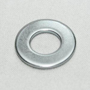 Metal washer lying on light fabric surface, close-up view showing circular ring and hollow center.