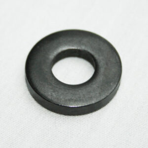 Black rubber flat washer with a central hole on a light surface