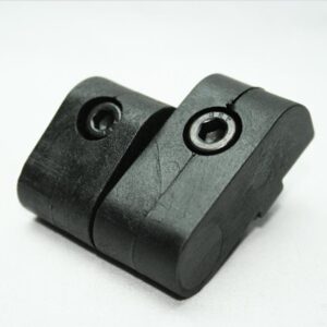 Two-part black plastic clamp with two metal bushings, resting on a white surface; appears cracked and worn.