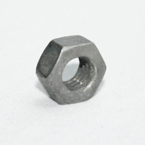 Metal hex nut resting on a white surface, seen from a slight angle