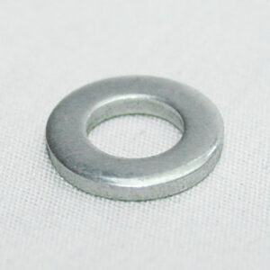 Metal washer with a circular hole resting on white fabric surface.