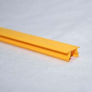 Close-up of a yellow plastic edging strip with a groove, resting on a pale surface.