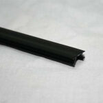 Close-up of a black rubber edge trim with a hollow channel on a light surface used as a seal or gasket, lying flat.
