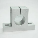 Silver machined metal clamp with a circular bore between two vertical jaws on a low, flat base.