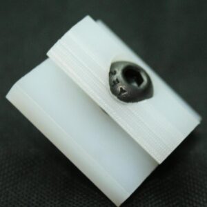 Close-up of a white plastic component with a fabric strap and a black recessed knob/fastener.