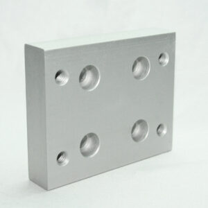 Rectangular silver aluminum mounting plate with six circular holes: four larger through-holes and two smaller threaded holes arranged in a grid, likely used as a fixture base.