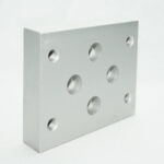 Silver square metal plate with multiple round holes, including a central large hole and several smaller threaded holes around it