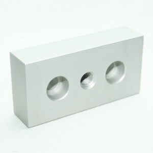 Silver rectangular metal block with three circular holes: two large, one threaded in the center on a white background.
