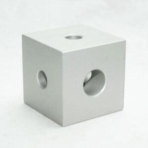 Silver metal cube with three circular holes on its faces (top and sides visible).