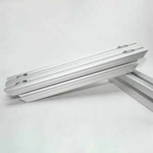 Set of silver aluminum profile rails with twin T-slot channels on each edge laid diagonally on a white background