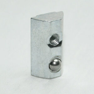 Small metallic rectangular block with two holes—one threaded and one ball-bearing insert—standing on a white surface.