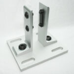 Silver metal mounting base with two vertical posts and adjustable clamps on a white surface, used to hold components in place.