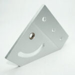 Silver metal mounting bracket with multiple holes and a curved crescent slot, angled diagonally toward the camera.