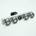 Bar-style control plate with four chrome knobs and a central black unit on a white background (instrument panel component).
