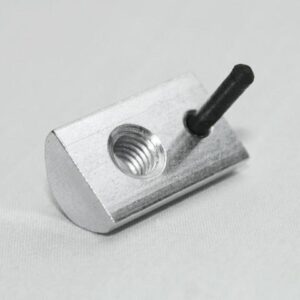 Metal block with a threaded hole and a black pin protruding from one end on a light surface.