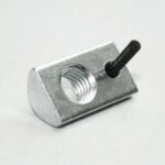 Close-up of a small silver metal block with a threaded hole and a short black pin protruding from its side.