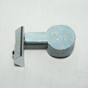 Metal cam lock component with a circular Faztek knob and a rectangular bar protruding from it, on a light fabric background.