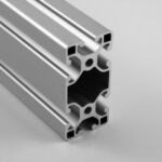 Close-up of a gray aluminum extrusion with multiple T-slots, revealing its hollow, grooved cross-section used in framing systems
