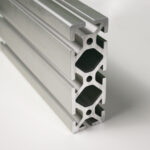 Close-up of a silver aluminum extrusion profile with multiple T-slot channels for modular framing systems.