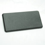 Rectangular black plastic object with rounded corners resting on a white surface.