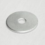 Flat silver metal washer with a central hole resting on a light surface.