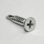 Close-up of a silver Phillips-head screw resting on a white surface