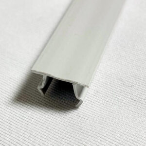 Close-up of a pale gray aluminum rail with a U-shaped channel at its end resting on a textured white surface